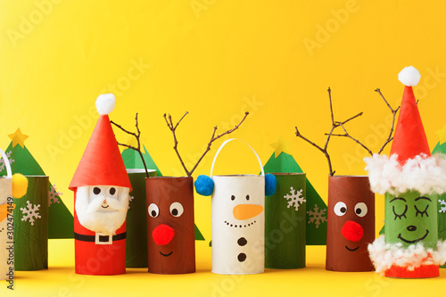 Merry christmas toy collection santa claus, snowman, tree, reindeer on yellow for Winter holiday concept background. Paper crafts, DIY. creative idea from toilet roll