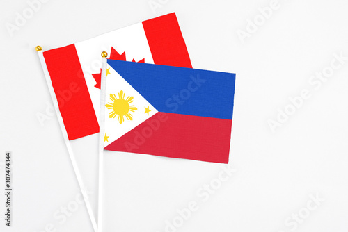 Philippines and Canada stick flags on white background. High quality fabric  miniature national flag. Peaceful global concept.White floor for copy space.