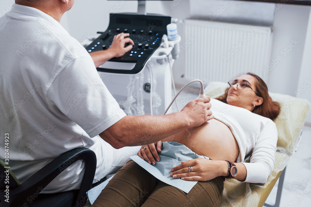 Obraz premium Male doctor does ultrasound for a pregnant woman in the hospital