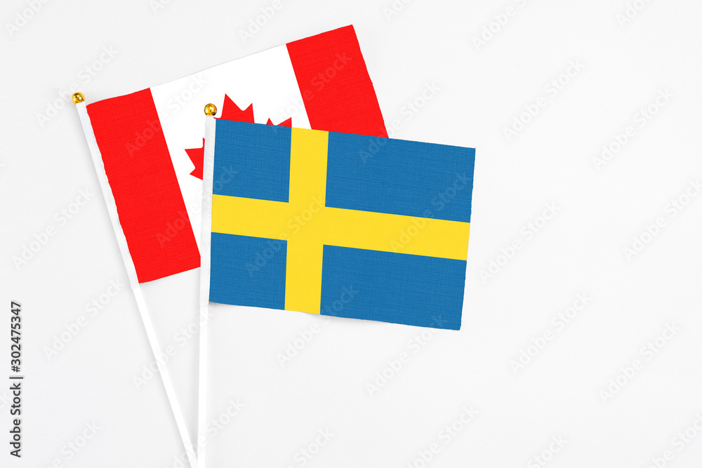 Sweden and Canada stick flags on white background. High quality fabric, miniature national flag. Peaceful global concept.White floor for copy space. Sweden and Canada stick flags on white background. High quality fabric, miniature national flag. Peaceful global concept.White floor for copy space.