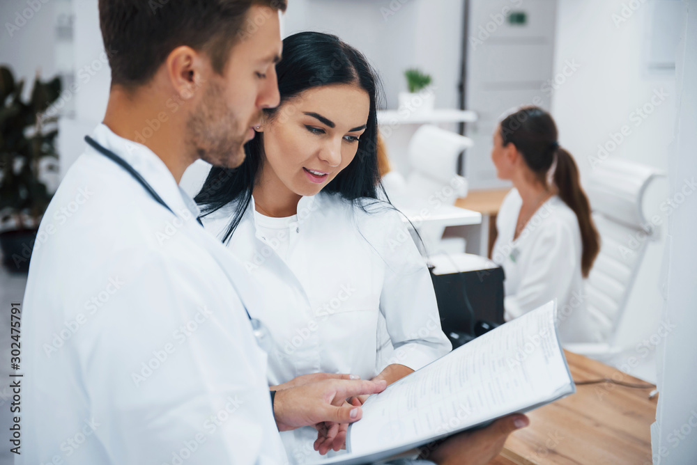 Doctor and brunette nurse stands in the hospital and talking at the work Doctor and brunette nurse stands in the hospital and talking at the work