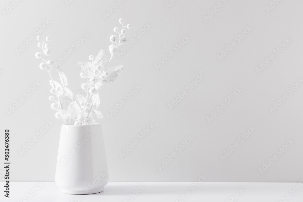 Winter composition of white branches, berries and leaves with sparkles in vase on white background. Christmas, New Year, winter concept. Front view, copy space