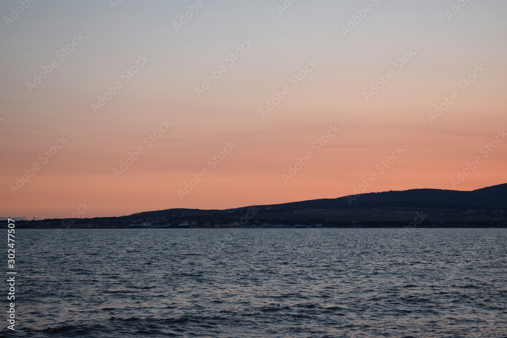 Sunset over the sea. The Sun sets behind the mountains