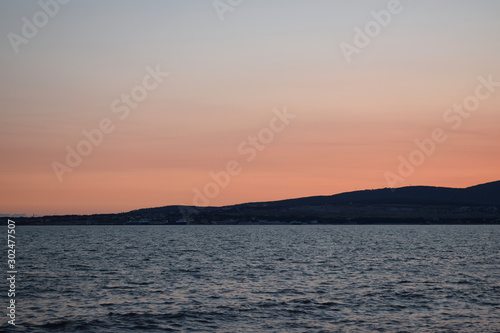 Sunset over the sea. The Sun sets behind the mountains