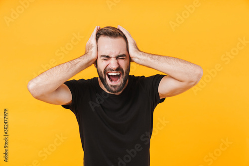 Image of nervous man in basic black t-shirt screaming and grabbing head photo