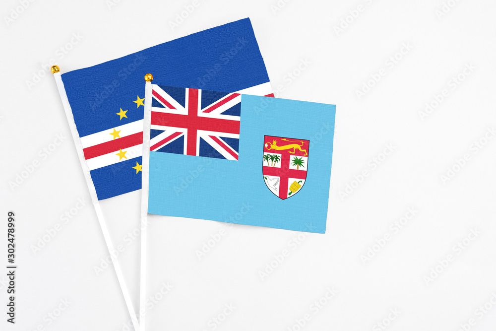 Fototapeta premium Fiji and Cape Verde stick flags on white background. High quality fabric, miniature national flag. Peaceful global concept.White floor for copy space.