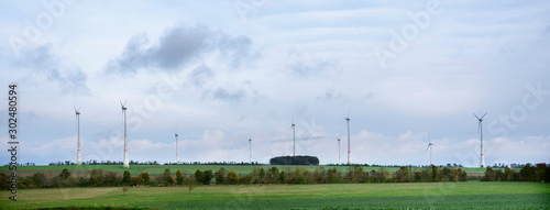 wind turbines and green fields under blue cloudy sky in german eifel