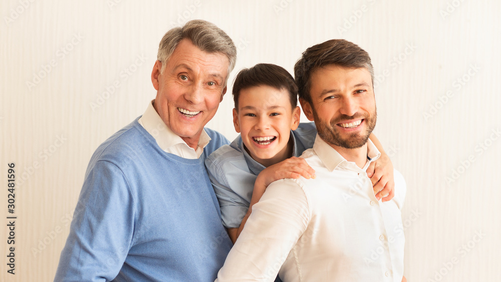 Smiling Boy, Father And Grandfather Hugging Standing Against White Background Smiling Boy, Father And Grandfather Hugging Standing Against White Background