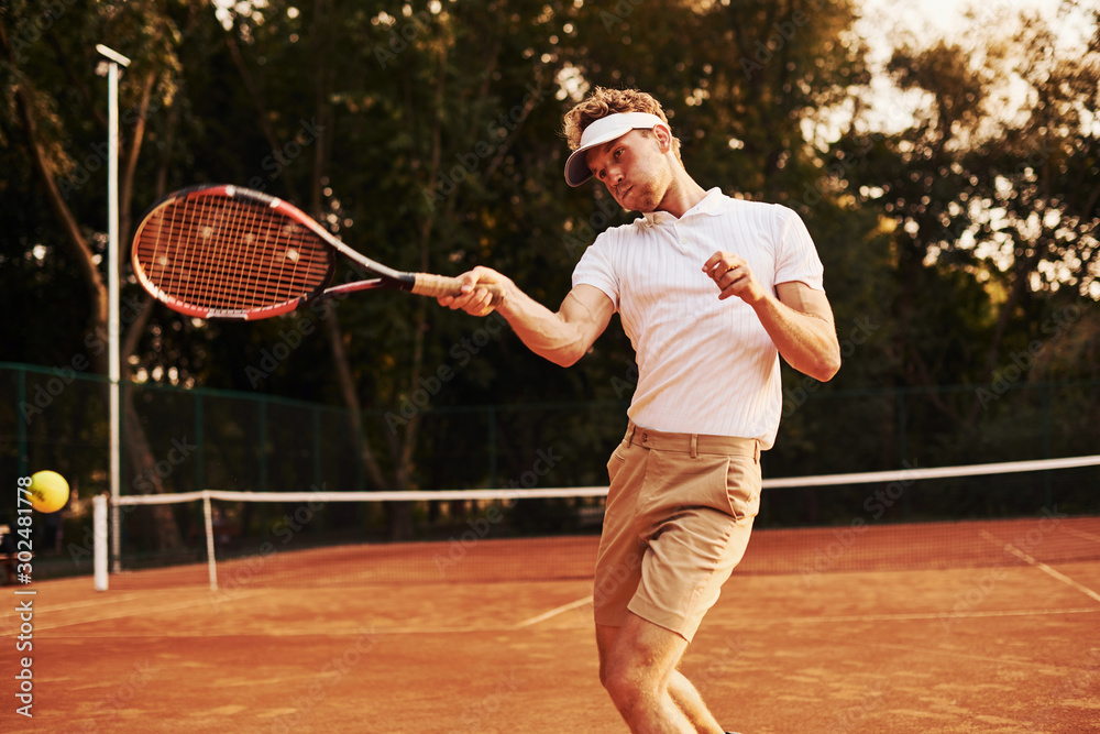Game in action. Young tennis player in sportive clothes is on the court outdoors