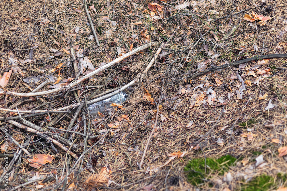 White plastic bottle on the ground in a pine forest. White plastic bottle on the ground in a pine forest.