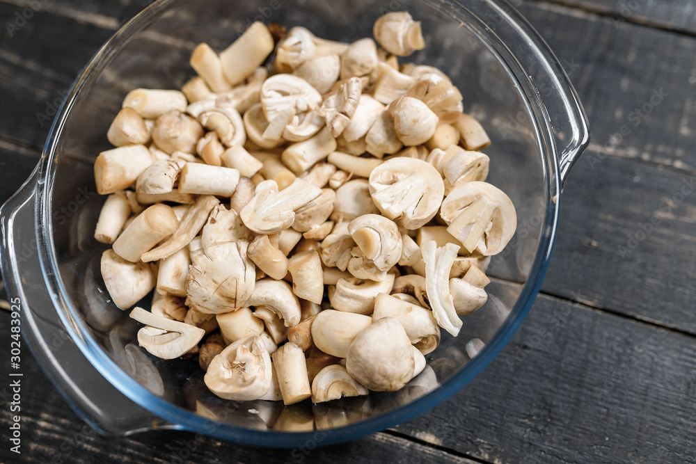 Cut forest champignons in glass bowl on black boards. Mushrooms on dark background. Cut forest champignons in glass bowl on black boards. Mushrooms on dark background.