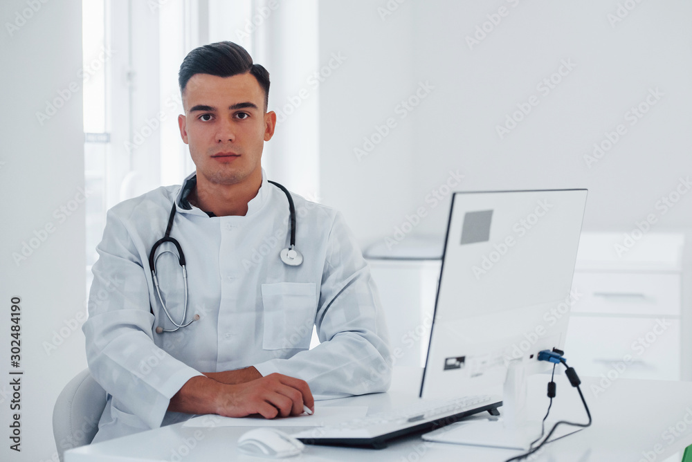 Young stylish male doctor with stethoscope is in clinic at daytime