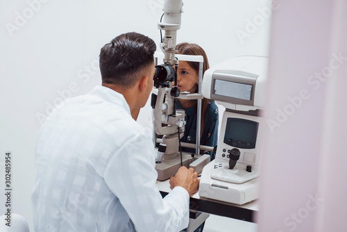 Young ophthalmologist is with little female visitor in the clinic