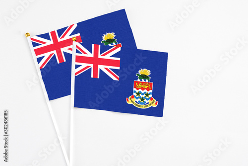 Cayman Islands and Cayman Islands stick flags on white background. High quality fabric, miniature national flag. Peaceful global concept.White floor for copy space. photo