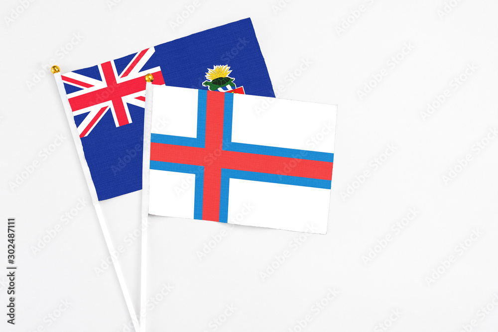 Faroe Islands and Cayman Islands stick flags on white background. High quality fabric, miniature national flag. Peaceful global concept.White floor for copy space.