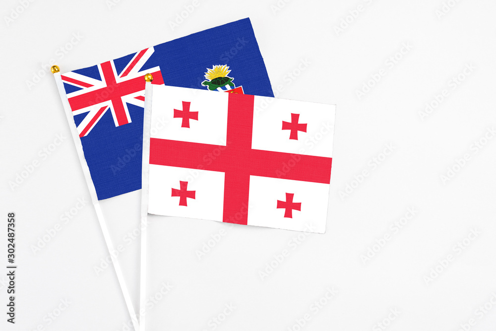 Georgia and Cayman Islands stick flags on white background. High quality fabric, miniature national flag. Peaceful global concept.White floor for copy space.