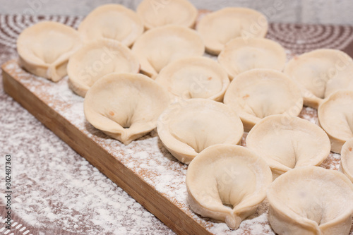 Dumplings - a dish of Russian cuisine on a wooden background. Cooking.