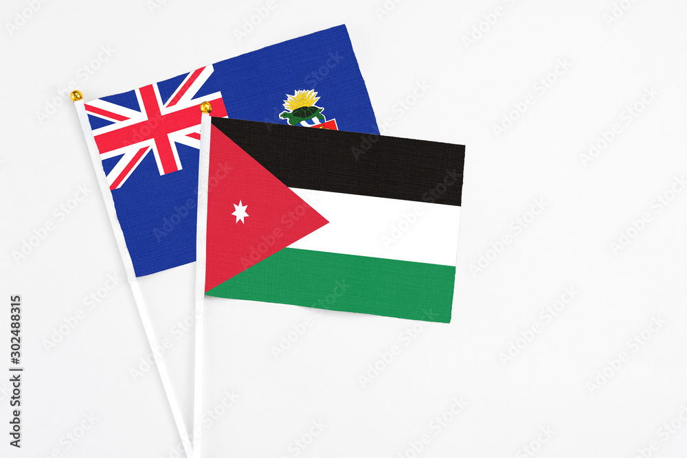 Jordan and Cayman Islands stick flags on white background. High quality fabric, miniature national flag. Peaceful global concept.White floor for copy space.