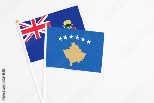 Kosovo and Cayman Islands stick flags on white background. High quality fabric, miniature national flag. Peaceful global concept.White floor for copy space. © sezerozger