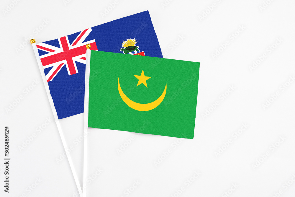 Mauritania and Cayman Islands stick flags on white background. High quality fabric, miniature national flag. Peaceful global concept.White floor for copy space. Mauritania and Cayman Islands stick flags on white background. High quality fabric, miniature national flag. Peaceful global concept.White floor for copy space.