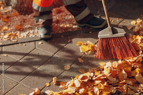 Obraz na plátně Janitor cleaner sweeping autumn leaves on the street