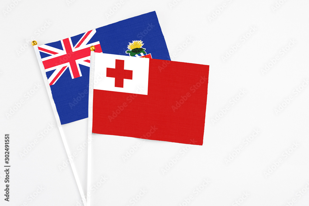 Tonga and Cayman Islands stick flags on white background. High quality fabric, miniature national flag. Peaceful global concept.White floor for copy space.