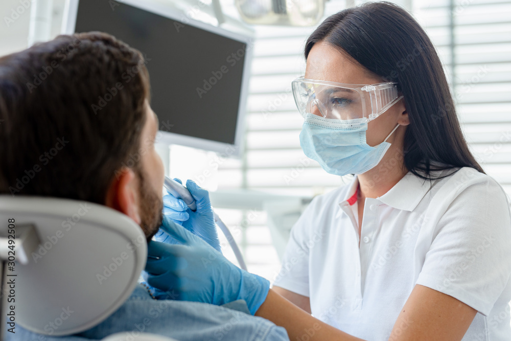 dentist at procedure using dental drill for client in modern dental clinic dentist at procedure using dental drill for client in modern dental clinic