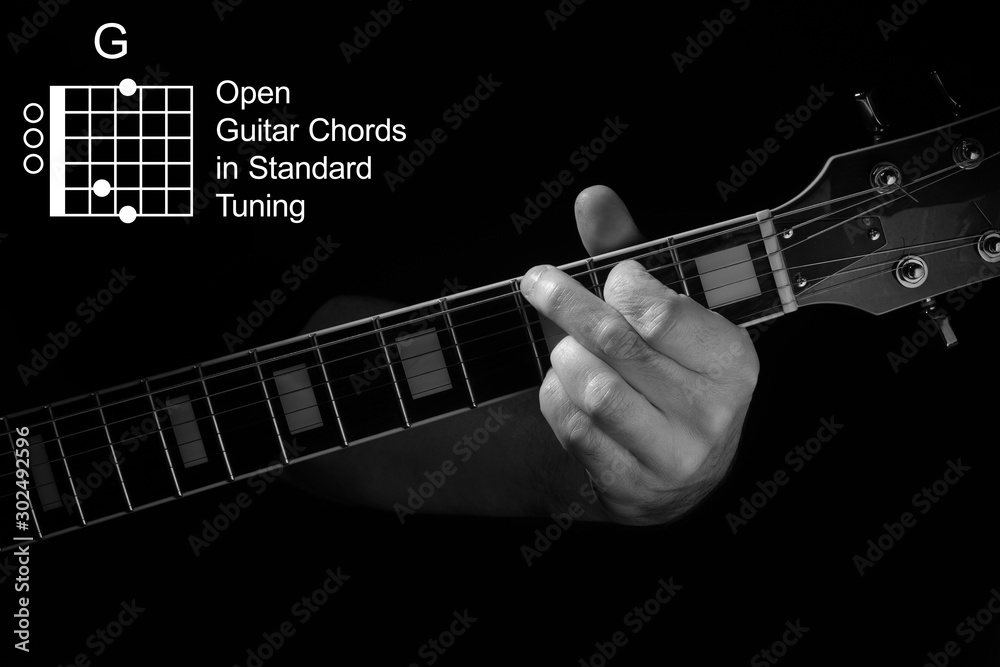 Fotka „Open Guitar Chords in Standard Tuning guitar tutorial series.  Closeup of hand playing G chord on guitar, on black background. Black and  white photo.“ ze služby Stock | Adobe Stock