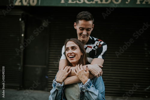 Young laughing couple embracing in urban area