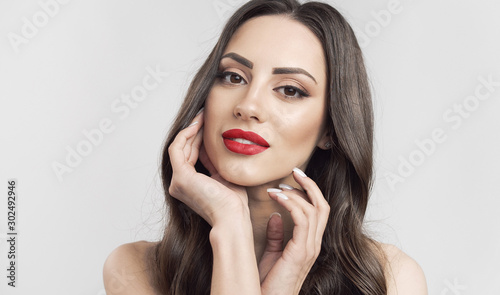 Fotografie, Obraz Portrait of brown hair cute woman with red lips touching her soft skin isolated