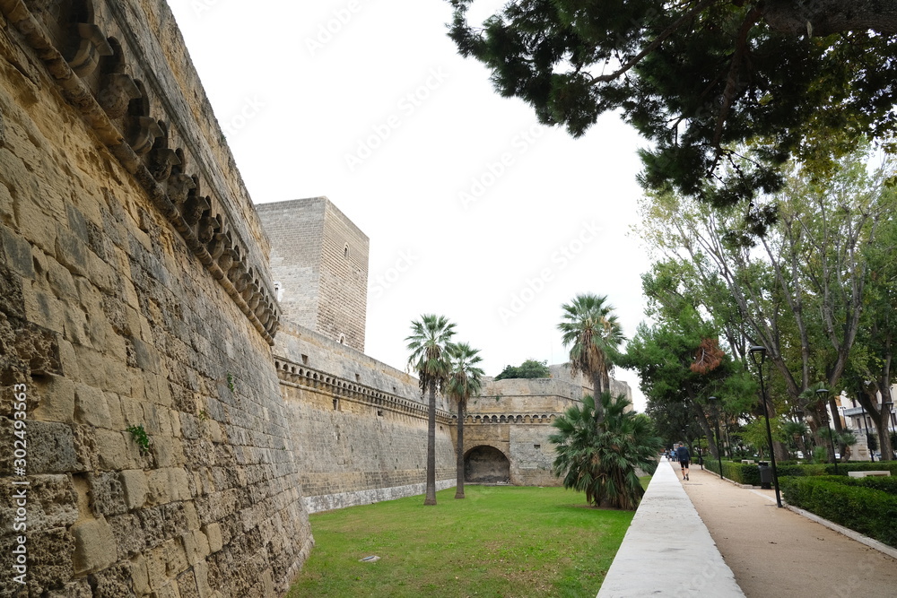 Walls of the Norman Swabian castle of Bari. The gardens with green plants and the fort built by Frederick II..