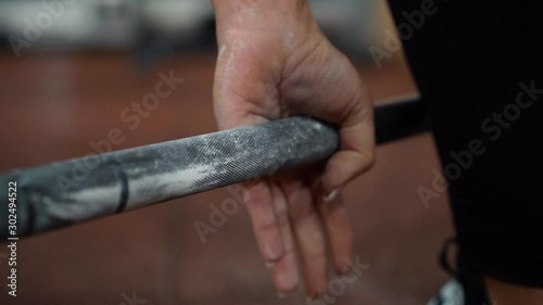 Woman getting ready for training, holding barbell, hand close up