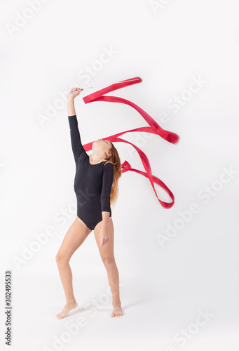 girl gymnast trains with a gymnastics tape on white background. children's professional sports.