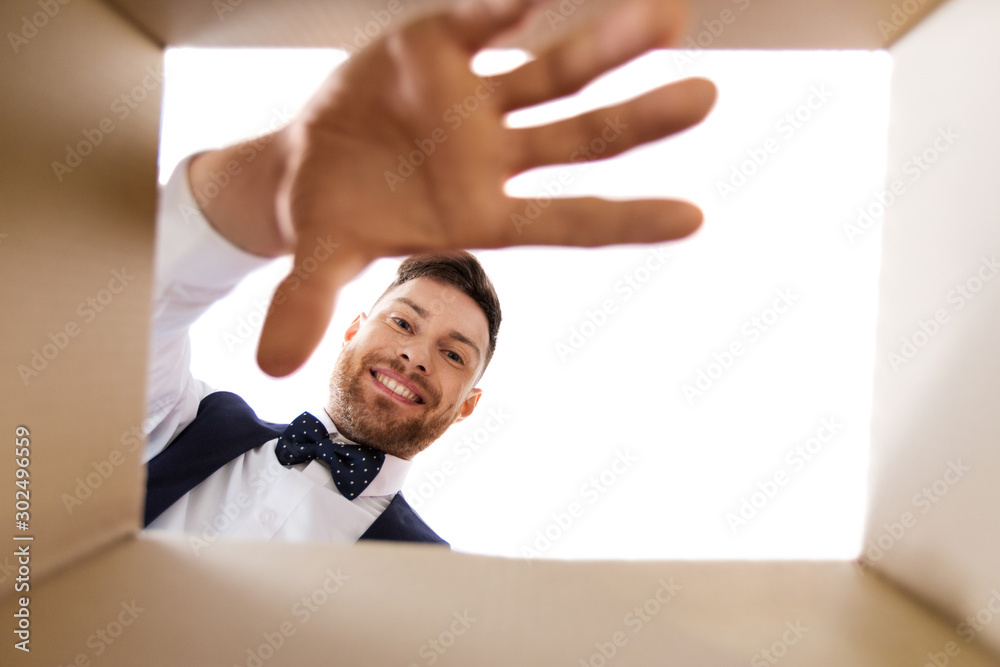 surprise, delivery and holidays concept - happy young man looking into open gift box surprise, delivery and holidays concept - happy young man looking into open gift box