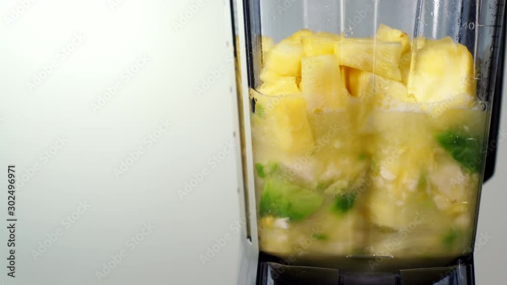 Making fresh fruits smoothie in blender. Pineapple ananas and banana fruit slices being mixing in jar. Healthy nutritious food, dieting