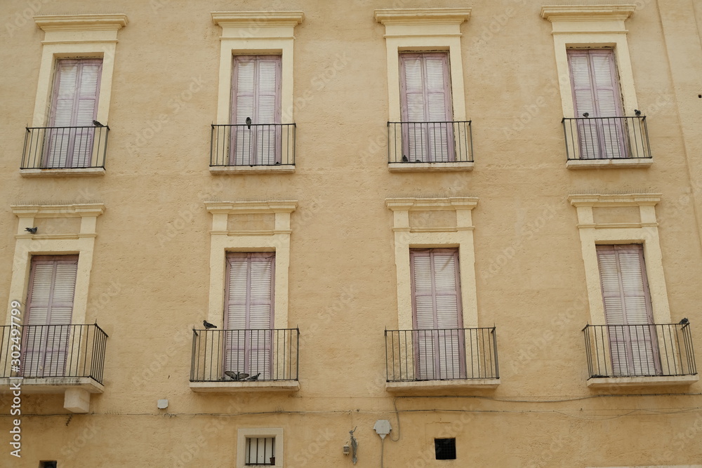 Facade of a Mediterranean palace with windows and balconies. Beige color plaster.
