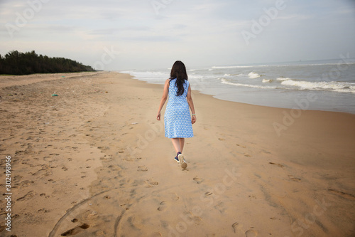 Back view of indian woman walking across beach