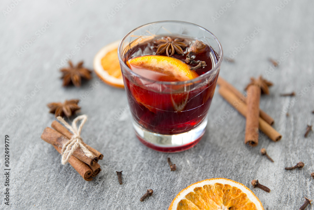 christmas and seasonal drinks concept - hot mulled wine, dry orange slices, raisins with cashew nuts and aromatic spices on grey background christmas and seasonal drinks concept - hot mulled wine, dry orange slices, raisins with cashew nuts and aromatic spices on grey background
