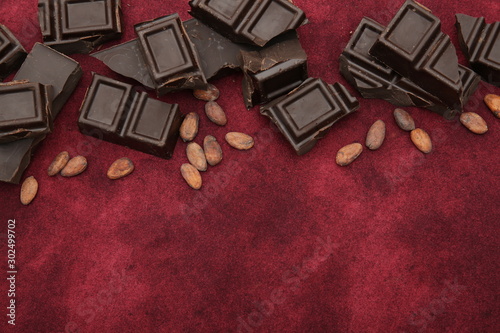 dark bitter chocolate with organic cocoa beans on a red background with copy space for text. Confectionery ingredient. Background, pattern, postcard, menu. Flat lay. Top view.