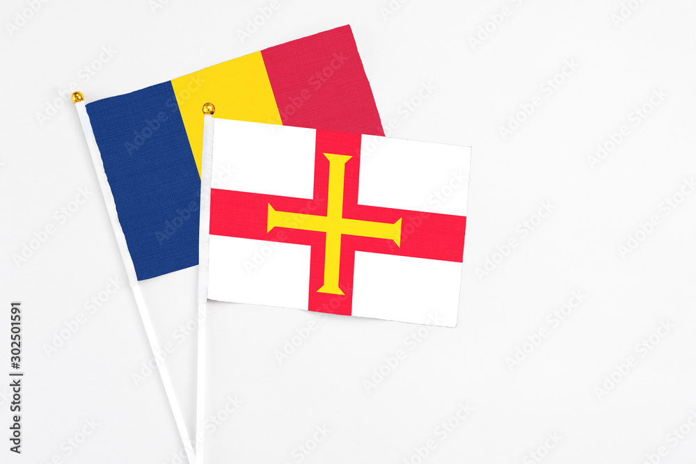 Guernsey and Chad stick flags on white background. High quality fabric, miniature national flag. Peaceful global concept.White floor for copy space.