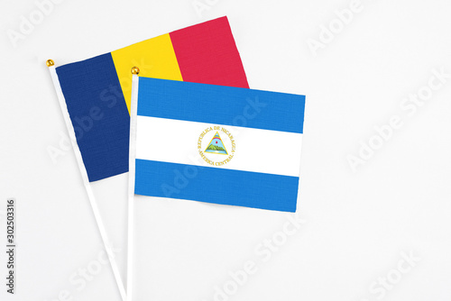 Nicaragua and Chad stick flags on white background. High quality fabric, miniature national flag. Peaceful global concept.White floor for copy space. photo