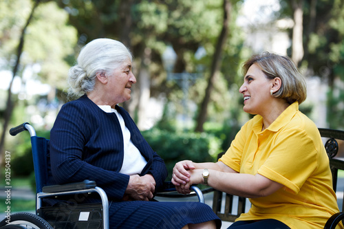 Professional helpful caregiver and handicapped senior woman. photo