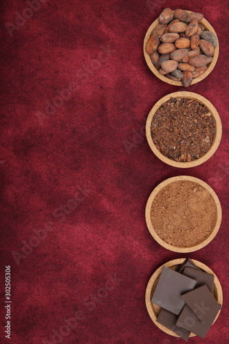 organic cacao beans, cocoa powder, ground and chocolate on a red background with copy space for text. Flat lay, top view. Ingredient. Vegan food. Background, pattern, card, menu. Vertical photo.
