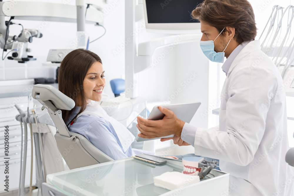 Dentist doctor showing patient results of treatment on digital tablet