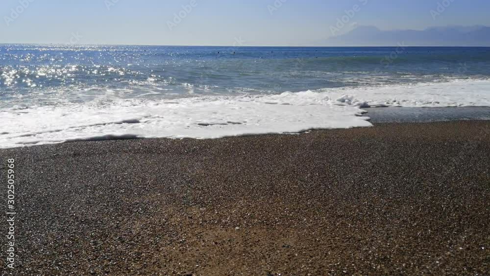 Huge waves are breaking on a sandy-stone beach, the sea against the backdrop of mountains - 22s. Troubled ocean on a sunny summer day Huge waves are breaking on a sandy-stone beach, the sea against the backdrop of mountains - 22s. Troubled ocean on a sunny summer day
