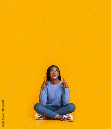 Excited black girl in blue pointing at copy space © Prostock-studio