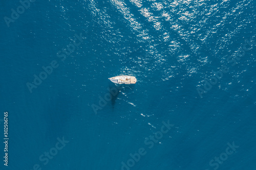 Aerial photo of small vessel cruising in tropical emerald clear sea.
