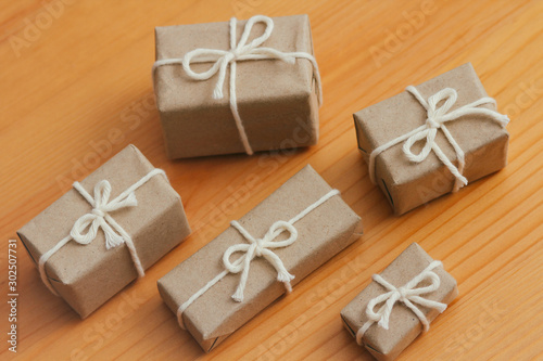 Set of parcels wrapping in brown craft paper and tie hemp string. Package. Delivery service. Online shopping. Your purchase. Gift box on a table. Isolation on white. Decorative wood background.