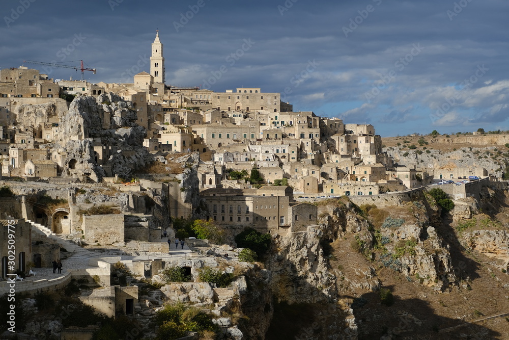 Panorama of the Sassi of Matera with houses in tuff stone. Church and bell tower at dawn with sky and clouds.