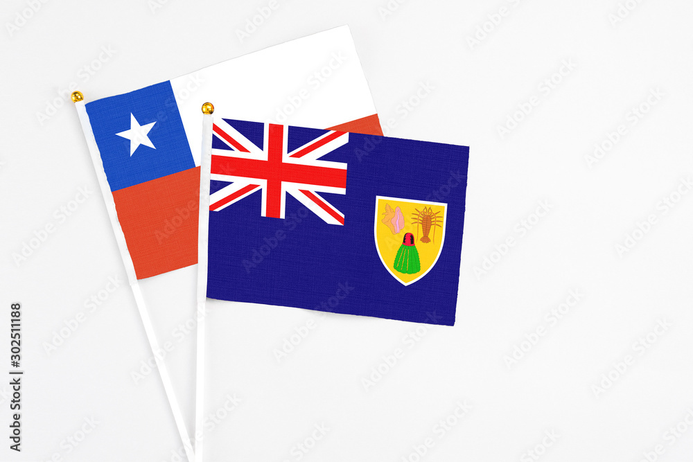 Fototapeta premium Turks And Caicos Islands and Chile stick flags on white background. High quality fabric, miniature national flag. Peaceful global concept.White floor for copy space.
